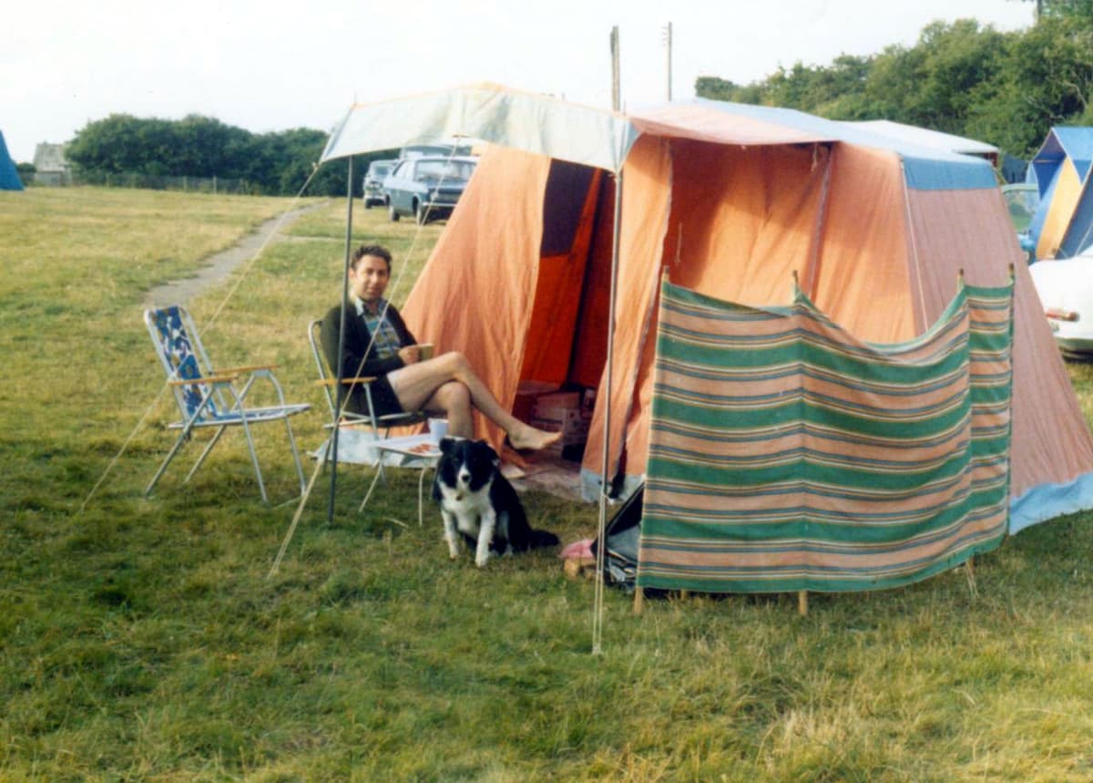 A tent pitched at the site in 1979, with a dog and folding chairs